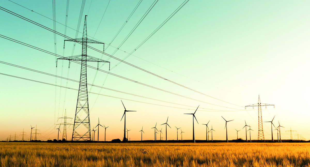 Strommasten, Kornfeld und Windenergieanlagen im herbstlichen Gegenlicht